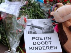 Цветы, игрушки и плакат в память о детях, погибших на 