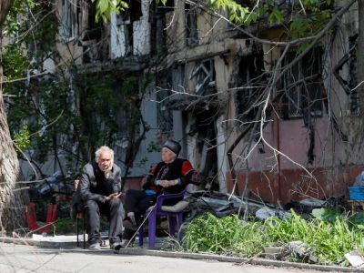 Мариупольцы сидят во дворе возле многоквартирного дома, сильно пострадавшего от обстрелов. Фото: Alexander Ermochenko / Reuters